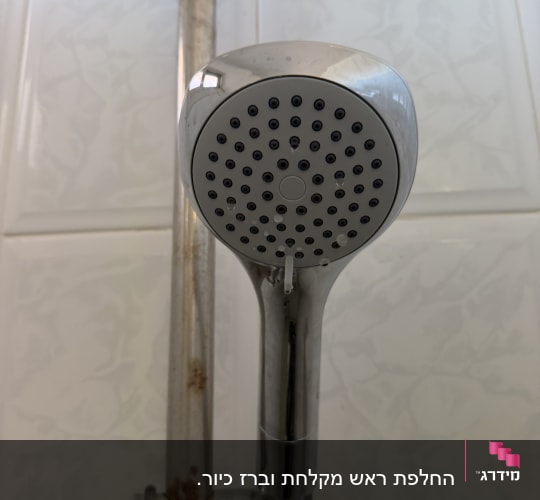 ראש מקלחת עם צינור חלוד על קיר